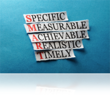 Specific Measurable Achievable Realistic and Timely all on pieces of paper on a blue background